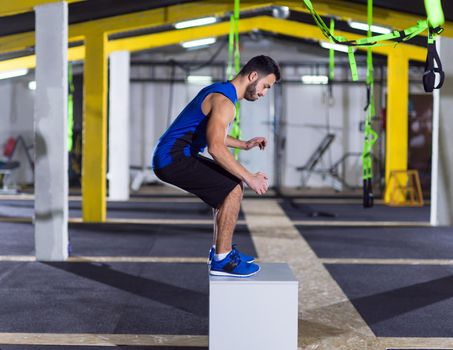 young athletic man training  jumping on fit box at fitness gym