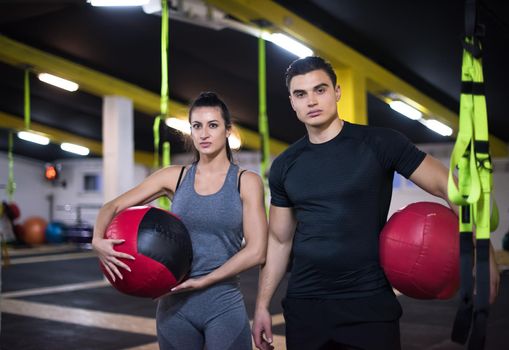 young athletes couple working out with medical ball at cross fitness gym