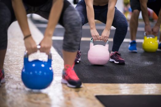 group of healthy young athletes doing exercises with kettlebells at cross fitness studio