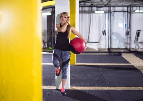 Portrait of beautiful athlete woman with red medicine  ball at crossfitness gym