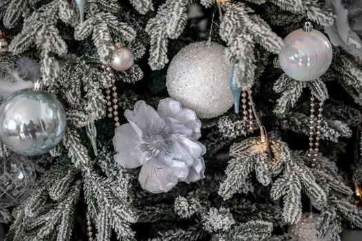 Close-up of a festively decorated outdoor Christmas tree with balls on a blurred sparkling fairy background. Defocused garland lights, bokeh effect