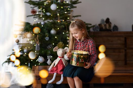 Girl with the presents sits near the Christmas tree