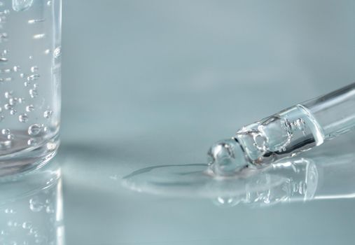 Pipette with fluid hyaluronic acid on blue background. Cosmetics and healthcare concept closeup. Dose of serum or retinol with air bubbles. Flat lay. Luxury gel or beauty product presentation in macro