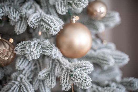 Close-up of a festively decorated outdoor Christmas tree with balls on a blurred sparkling fairy background. Defocused garland lights, bokeh effect