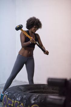 Sledgehammer Tire Hits african american woman workout at gym with hammer and tractor tire