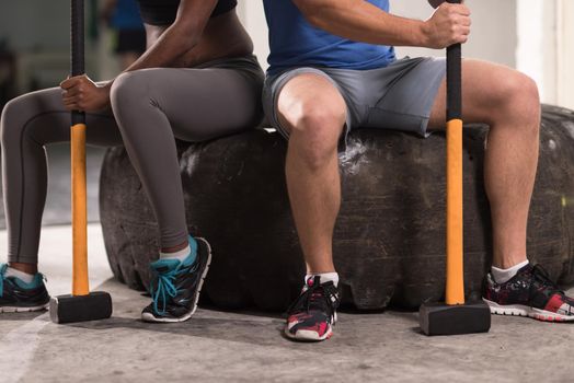 portrait of a young multiethnic couple after training with a sledgehammer and tractor tire