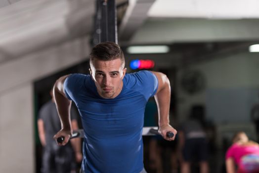 young muscular bodybuilder working out in gym doing exercises parallel bars  Concept sport