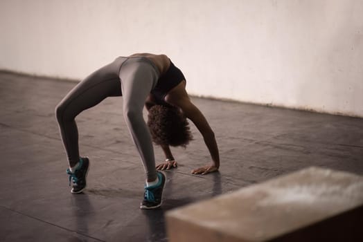 Beautiful young african american woman working out , doing yoga exercise, stretching, standing in Bridge Pose in the gym