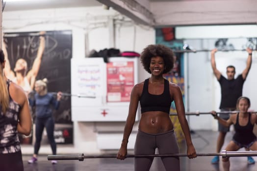 Young Cute african american sport woman in fitness room lifting empty bar