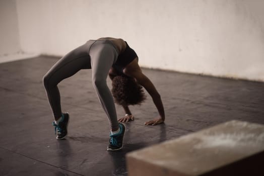 Beautiful young african american woman working out , doing yoga exercise, stretching, standing in Bridge Pose in the gym