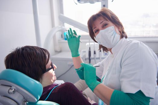 Closeup of a woman patient at the dentist waiting to be checked up with the woman doctor in the background