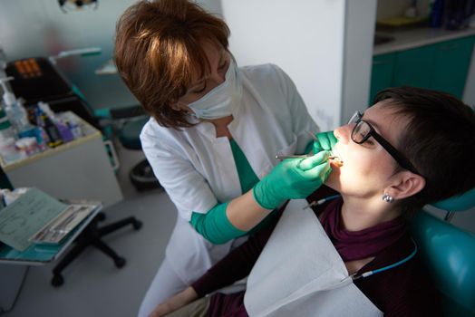 Closeup of a woman patient at the dentist waiting to be checked up with the woman doctor in the background