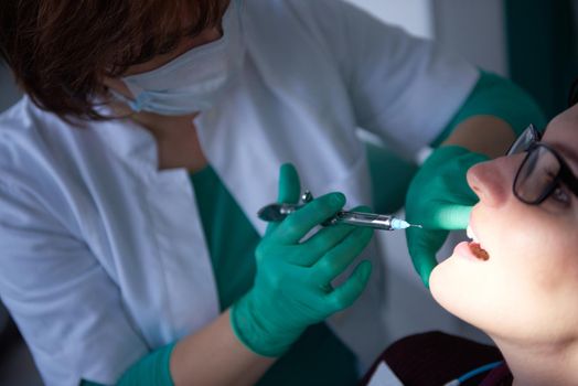 Closeup of a woman patient at the dentist waiting to be checked up with the woman doctor in the background