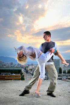 romantic urban couple dancing on top of the bulding