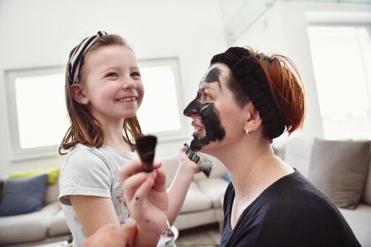 Family at home beauty treatment during coronavirus pandemic stay at home quarantine. Mother and little girl daughter  make a facial mask.