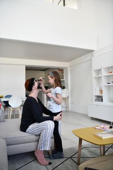 Family at home beauty treatment during coronavirus pandemic stay at home quarantine. Mother and little girl daughter  make a facial mask.