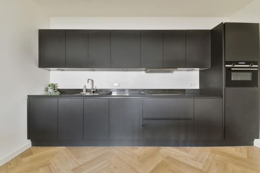 Black all-wall kitchen set in modern kitchen with parquet floor