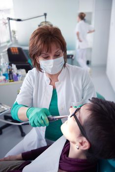 Closeup of a woman patient at the dentist waiting to be checked up with the woman doctor in the background