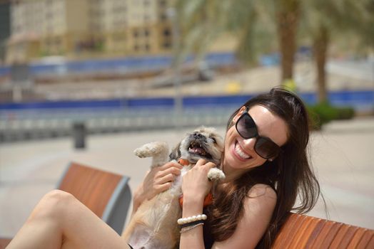 beautiful happy young  woman in black dress with cute small dog puppy have fun on street