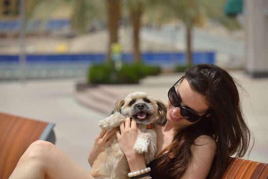 beautiful happy young  woman in black dress with cute small dog puppy have fun on street