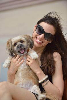 beautiful happy young  woman in black dress with cute small dog puppy have fun on street