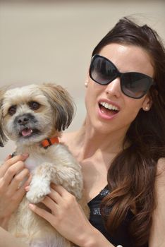 beautiful happy young  woman in black dress with cute small dog puppy have fun on street