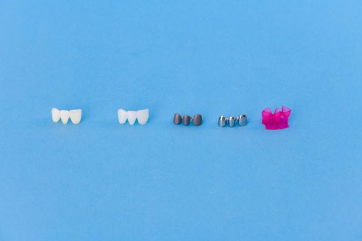 different types of dental tooth crowns isolated on blue background