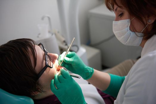 Closeup of a woman patient at the dentist waiting to be checked up with the woman doctor in the background