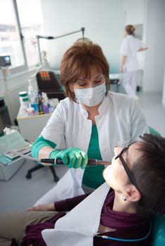 Closeup of a woman patient at the dentist waiting to be checked up with the woman doctor in the background