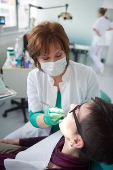 Closeup of a woman patient at the dentist waiting to be checked up with the woman doctor in the background