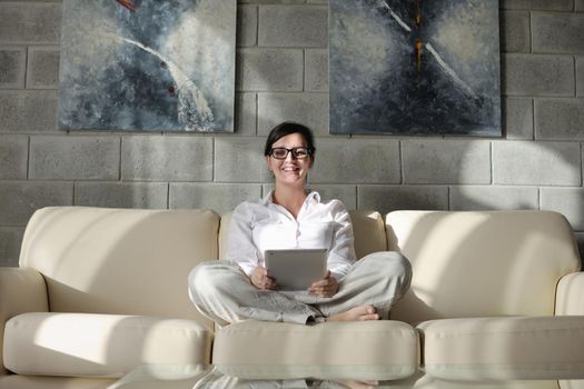 Young woman at home relaxing in her lliving room reading a digital tablet PC surf internet and work