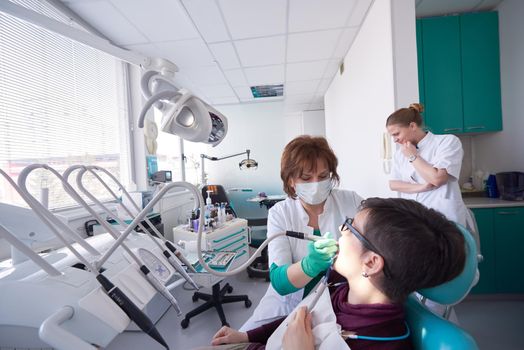 Closeup of a woman patient at the dentist waiting to be checked up with the woman doctor in the background