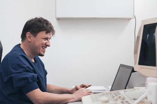 Orthopedist doctor examining X-ray picture at a desk in clinic on a laptop computer. High quality photo. Selective focus