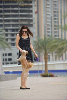 beautiful happy young  woman in black dress with cute small dog puppy have fun on street