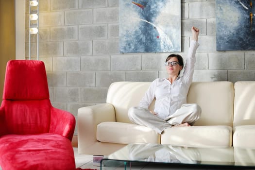 happy young woman relax at home on sofa in bright living room and watching tv