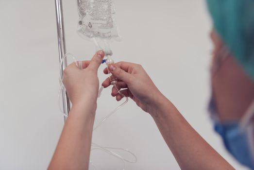 General practitioner holding intravenous drip infusion. Doctor handling IV fluid drip with copy space on white background.Nurse Team performing Intravenous therapy. High quality photo.Selective focus.