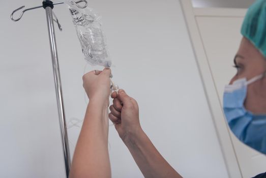 General practitioner holding intravenous drip infusion. Doctor handling IV fluid drip with copy space on white background.Nurse Team performing Intravenous therapy. High quality photo.Selective focus.