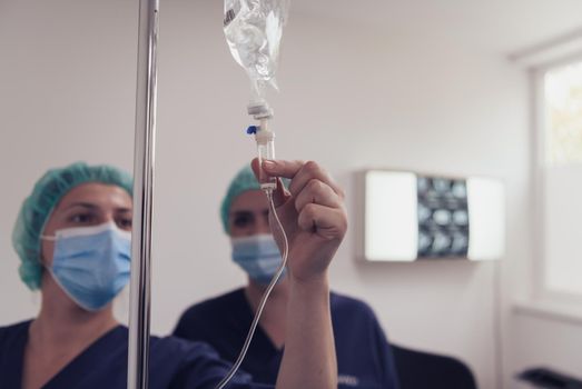 General practitioner holding intravenous drip infusion. Doctor handling IV fluid drip with copy space on white background.Nurse Team performing Intravenous therapy. High quality photo.Selective focus.