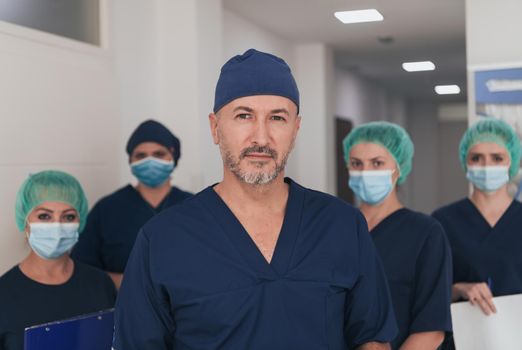 Orthopedic doctor in front of his medical multiethnic team wearing a face mask during covid-19 outbreak. Surgeon in front of his colleagues. Selective focus.