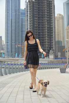 beautiful happy young  woman in black dress with cute small dog puppy have fun on street