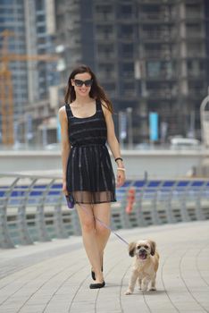 beautiful happy young  woman in black dress with cute small dog puppy have fun on street