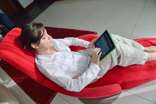 Young woman at home relaxing in her lliving room reading a digital tablet PC surf internet and work