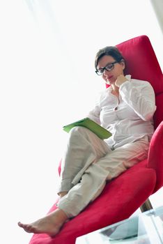 Young woman at home relaxing in her lliving room reading a digital tablet PC surf internet and work