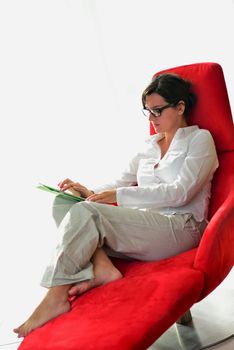 Young woman at home relaxing in her lliving room reading a digital tablet PC surf internet and work