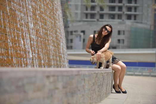 beautiful happy young  woman in black dress with cute small dog puppy have fun on street