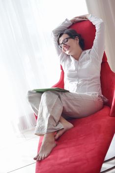 Young woman at home relaxing in her lliving room reading a digital tablet PC surf internet and work