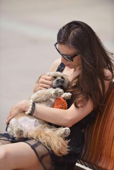 beautiful happy young  woman in black dress with cute small dog puppy have fun on street