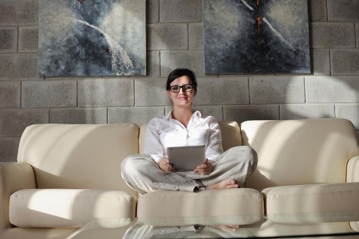 Young woman at home relaxing in her lliving room reading a digital tablet PC surf internet and work