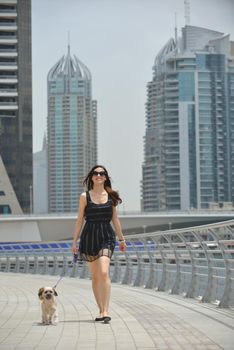 beautiful happy young  woman in black dress with cute small dog puppy have fun on street