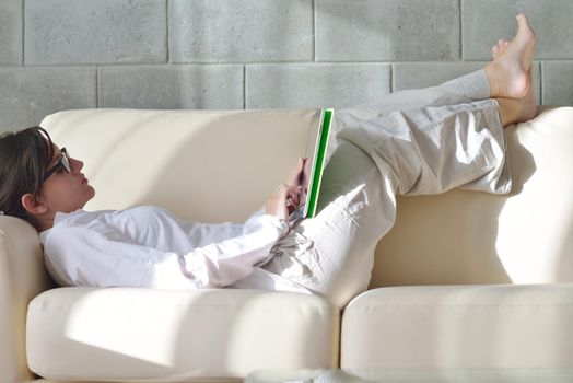 Young woman at home relaxing in her lliving room reading a digital tablet PC surf internet and work